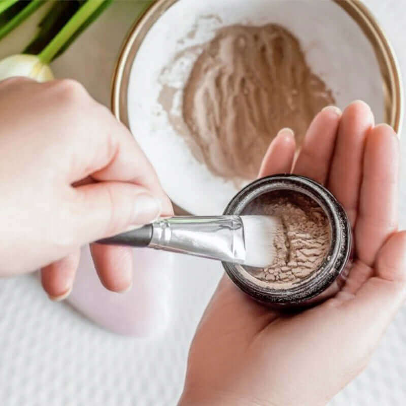 Woman mixing Atonement Superfood clay face mask with water ready for application