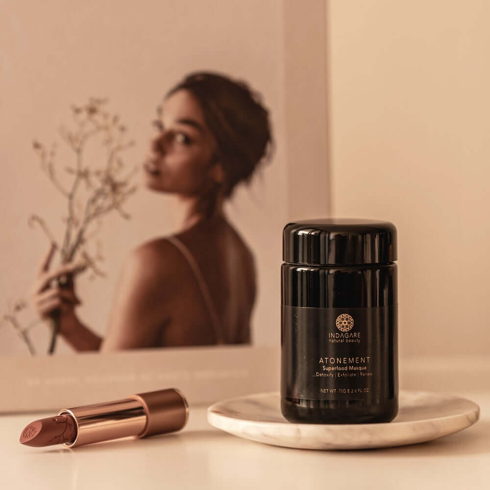Atonement Superfood clay face mask sitting on the bathroom vanity with reflection of woman in the background mirror