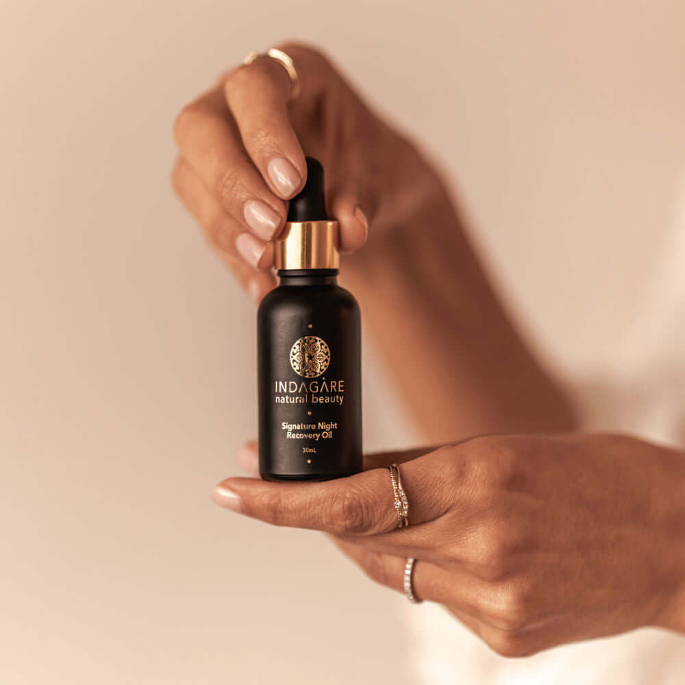 Woman's hands holding up a bottle of Signature Night Recovery Oil