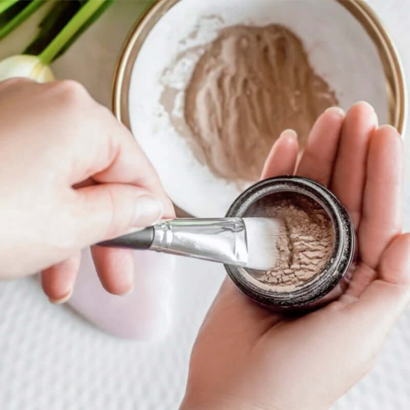 Woman mixing Atonement Superfood clay face mask with water ready for application
